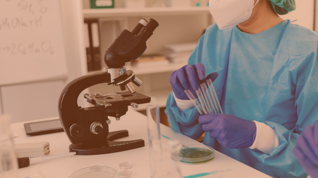 Travailleuse tenant des tubes devant un microscope